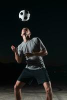 retrato do uma jovem bonito futebol jogador homem em uma rua jogando com uma futebol bola. foto