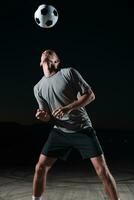 retrato do uma jovem bonito futebol jogador homem em uma rua jogando com uma futebol bola. foto