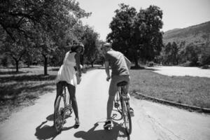 jovem casal multiétnico dando um passeio de bicicleta na natureza foto