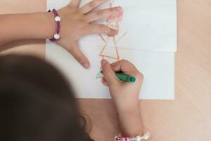 pequeno meninas sentado dentro elementar escola desenhando em papel foto