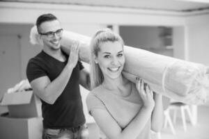 casal carregando um tapete se mudando para nova casa foto