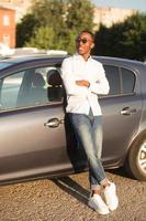 feliz afro-americano ao lado de um carro no verão foto
