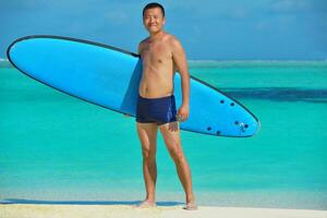 homem com prancha de surf na praia foto