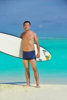 homem com prancha de surf na praia foto