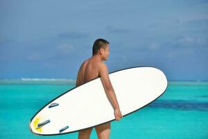 homem com prancha de surf na praia foto