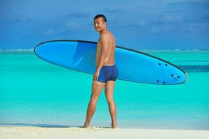 homem com prancha de surf na praia foto