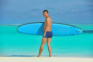 homem com prancha de surf na praia foto