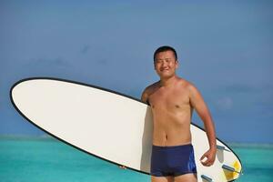 homem com prancha de surf na praia foto