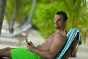 homem relaxando e use tablet na praia foto