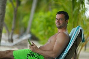 homem relaxando e use tablet na praia foto