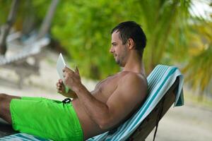 homem relaxando e use tablet na praia foto