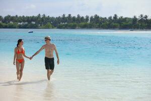 feliz casal jovem se divertir na praia foto