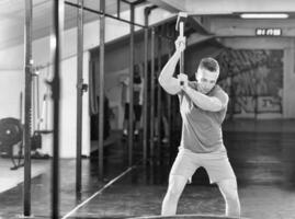 treino de homem com pneu de martelo e trator foto