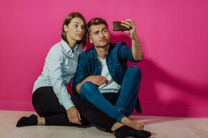 um jovem casal feliz sentado no chão em casa e fazendo selfie foto