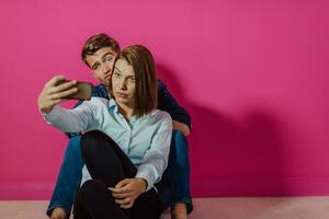 um jovem casal feliz sentado no chão em casa e fazendo selfie foto