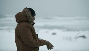 homem no inverno em clima de tempestade, vestindo jaqueta de pele quente foto