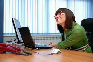 sorridente jovem empresária trabalhando em um laptop no escritório. foto