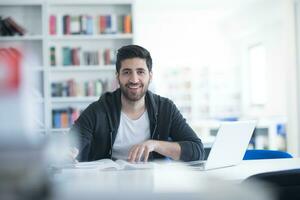 estudante na biblioteca da escola usando laptop para pesquisa foto