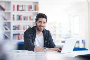 estudante na biblioteca da escola usando laptop para pesquisa foto