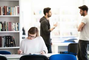 aluna estuda na biblioteca da escola, grupo de alunos em segundo plano foto