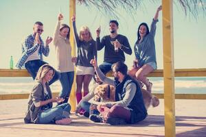 grupo de amigos se divertindo no dia de outono na praia foto