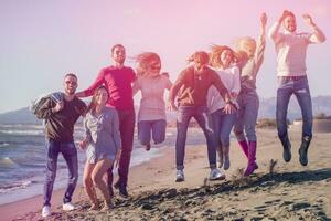 jovens amigos pulando juntos na praia de outono foto