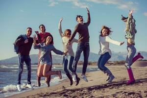 jovens amigos pulando juntos na praia de outono foto