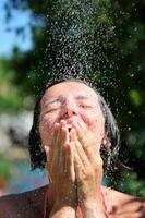 jovem mulher bonita relaxante sob o chuveiro foto