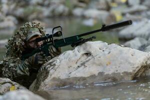 uma militares homem ou airsoft jogador dentro uma camuflar terno esgueirar-se a rio e mira a partir de uma Franco atirador rifle para a lado ou para alvo. foto