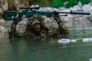 uma militares homem ou airsoft jogador dentro uma camuflar terno esgueirar-se a rio e mira a partir de uma Franco atirador rifle para a lado ou para alvo. foto