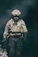 um soldado barbudo em um uniforme das forças especiais caminha por um prédio abandonado após uma missão bem-sucedida. foco de seleção foto