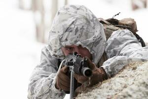 guerra de inverno nas montanhas árticas. operação em condições frias. soldado no uniforme camuflado de inverno no exército de guerra moderna em um dia de neve no campo de batalha da floresta com um rifle. foco seletivo foto