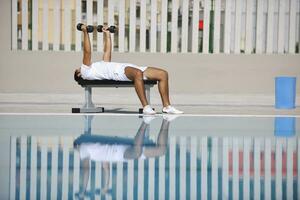 jovem homem exercício às à beira da piscina foto