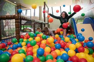 jovem mãe com seus filhos em uma sala de jogos infantil foto