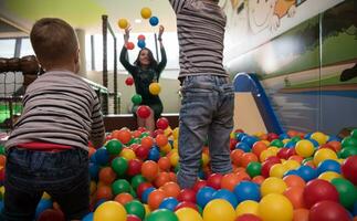 jovem mãe com seus filhos em uma sala de jogos infantil foto