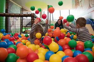 jovem mãe com seus filhos em uma sala de jogos infantil foto