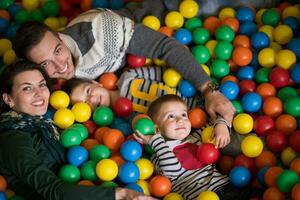 pais jovens com filhos em uma sala de jogos infantil foto