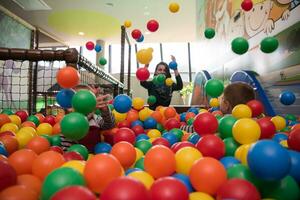 jovem mãe com seus filhos em uma sala de jogos infantil foto