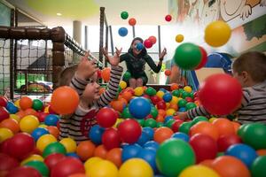 jovem mãe com seus filhos em uma sala de jogos infantil foto