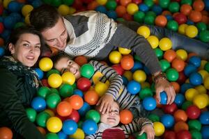 pais jovens com filhos em uma sala de jogos infantil foto