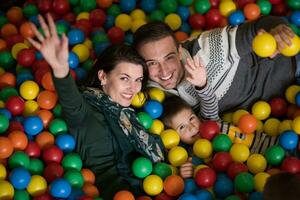 pais jovens com filhos em uma sala de jogos infantil foto