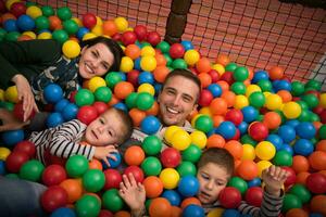 pais jovens com filhos em uma sala de jogos infantil foto