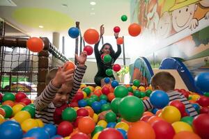 jovem mãe com seus filhos em uma sala de jogos infantil foto