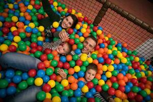 pais jovens com filhos em uma sala de jogos infantil foto