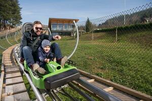 pai e filho gostam de dirigir na montanha-russa alpina foto