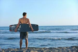 retrato de um jovem kitsurf na praia ao pôr do sol foto