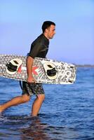 retrato de um jovem kitsurf na praia ao pôr do sol foto