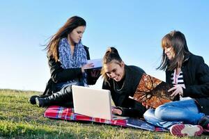 grupo de adolescentes trabalhando no laptop ao ar livre foto