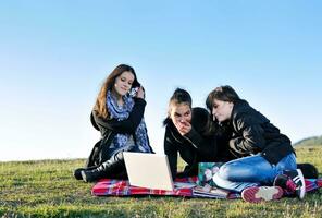 grupo de adolescentes trabalhando no laptop ao ar livre foto