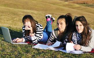 grupo de adolescentes trabalhando no laptop ao ar livre foto